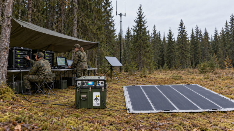 SUNS Energy Hub and solar mat beside a military field communications station in a forest.